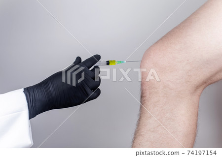 An orthopedic surgeon gives an injection in the knee. Treatment of osteoarthritis with hormonal drugs or drugs based on hyaluronic acid. Help with diseases that damage the cartilage of the joint An orthopedic surgeon gives an injection in the knee. Treatment of osteoarthritis with hormonal drugs or drugs based on hyaluronic acid. Help with diseases that damage the cartilage of the joint 74197154