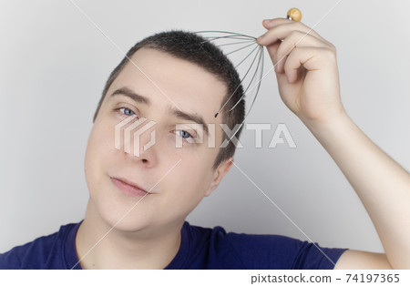 A man on a white background makes himself a head massage with a capillary massager. Self-help, anti-stress and relaxation concept A man on a white background makes himself a head massage with a capillary massager. Self-help, anti-stress and relaxation concept 74197365