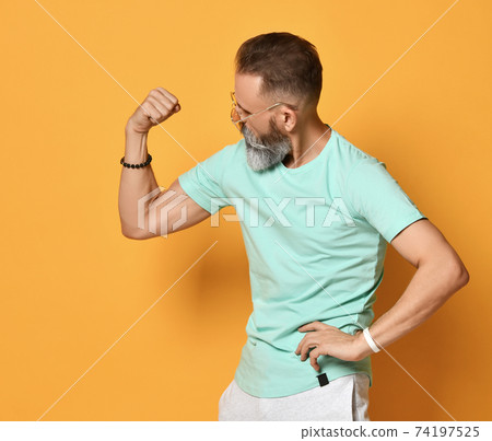 Brutal bearded man showing muscle power gesture Brutal bearded man showing muscle power gesture 74197525