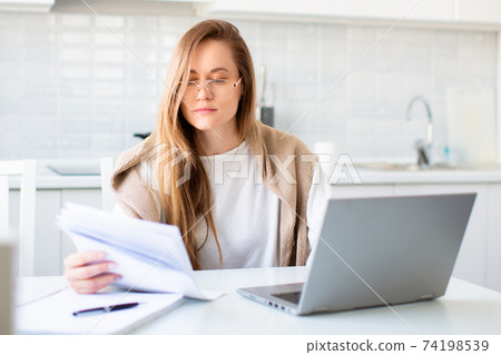 Photo of a woman in front of laptop monitor working with papers. Photo of a woman in front of laptop monitor working with papers. 74198539