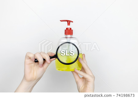 A woman examines the harmful ingredients of the liquid soap a magnifying glass. Harmful composition of ingredients. Means with SLS (sodium lauryl sulfate) A woman examines the harmful ingredients of the liquid soap a magnifying glass. Harmful composition of ingredients. Means with SLS (sodium lauryl sulfate) 74198673