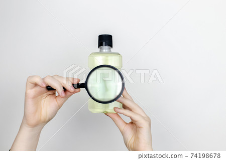 A woman is holding mouthwash. Place for your text. The concept of hazardous substances in cosmetics and household chemicals 74198678