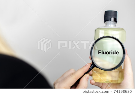 A woman examines the harmful ingredients of the mouthwash. Harmful composition of ingredients. Rinse aid with Fluoride. 74198680