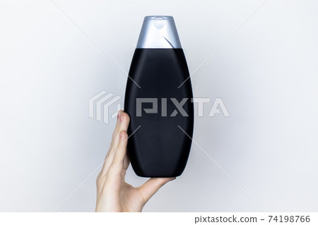 Chemical components of the shampoo. A woman's hand holds a black jar of shampoo. Place for text. Conception of the harm of chemical cosmetics or the benefits of organic chemicals for home Chemical components of the shampoo. A woman's hand holds a black jar of shampoo. Place for text. Conception of the harm of chemical cosmetics or the benefits of organic chemicals for home 74198766