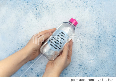 A bottle of micellar water floating in soapy water. Harmful composition of ingredients. The concept of hazardous substances in cosmetics and household chemicals 74199198