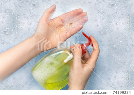 Bottles of detergents float in the foam. The concept of the dangers of household chemicals. Sodium laureate, parabens, sulfates and other chemical compounds in the foam. Liquid soap in a yellow jar 74199224