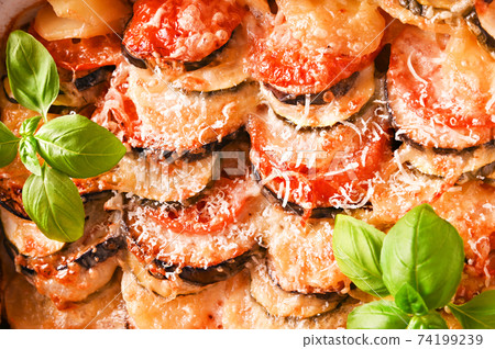Traditional italian food. Baked eggplant, tomatoes with sauce, parmesan and basil. Rustic food for a 74199239