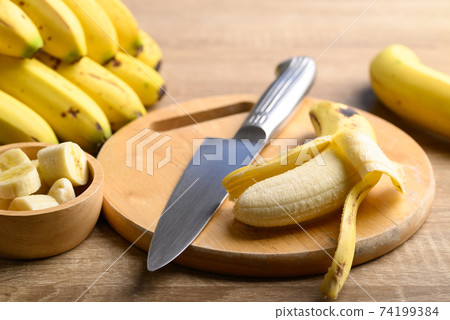 Ripe banana fruit with kitchen knife on wooden cutting board 74199384