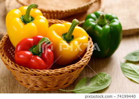Fresh yellow, red and green bell peppers in a bamboo basket  74199440