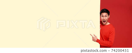 handsome asian man in red casual attire with hand pointing blank announcement banner background. handsome asian man in red casual attire with hand pointing blank announcement banner background. 74200431
