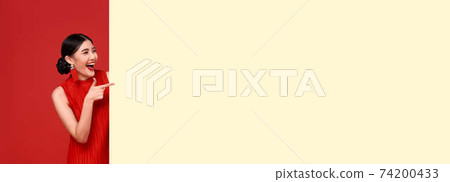 Happy asian woman in red casual attire with hand pointing blank announcement banner Happy asian woman in red casual attire with hand pointing blank announcement banner 74200433