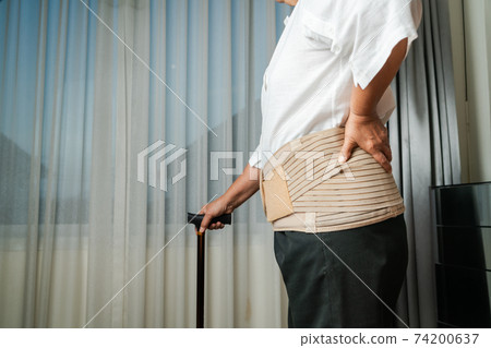 Senior back pain woman with walking stick at home Senior back pain woman with walking stick at home 74200637