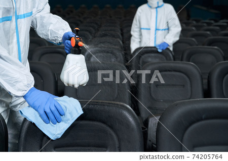 Workers cleaning chairs with disinfectants in cinema. Workers cleaning chairs with disinfectants in cinema. 74205764