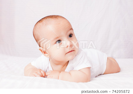 Adorable baby lying on the stomach at the white 74205872