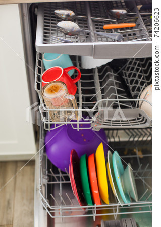 Putting dirty plates in the dishwasher after dinner 74206623