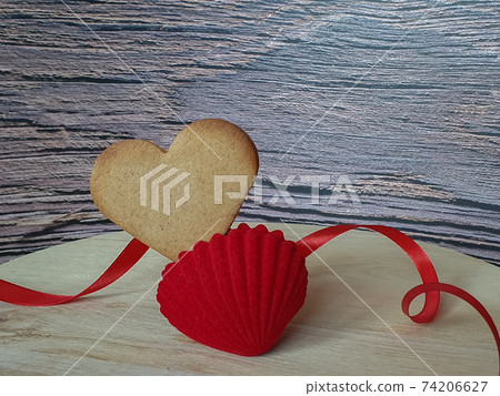 heart-shaped homemade gingerbread placed in a red jewelry box decorated with red ribbon on a light wooden background, Valentine's Day, greeting card, pastry, Copy space, top view, love concept 74206627