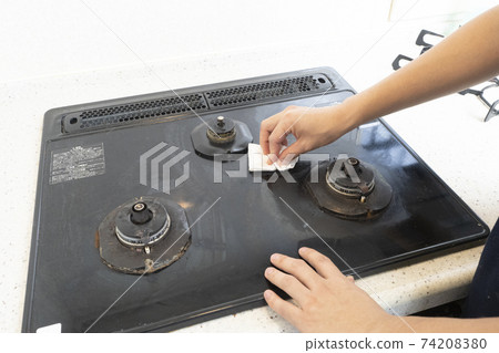 Hands of a male house cleaning worker cleaning a gas stove Hands of a male house cleaning worker cleaning a gas stove 74208380