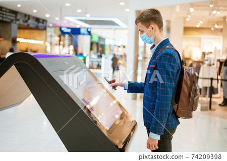 young man in the mall looks at the monitor in a mask 74209398