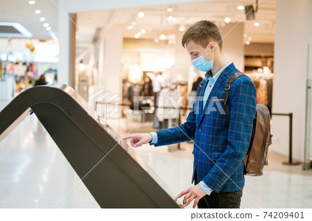 young man in the mall looks at the monitor in a mask 74209401