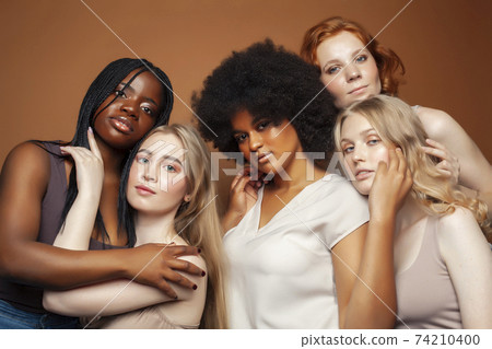 young pretty caucasian, afro, scandinavian woman posing cheerful together on brown background, lifestyle diverse nationality people concept 74210400