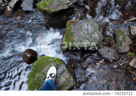 Footsteps across the stones of the mountain stream 74210711