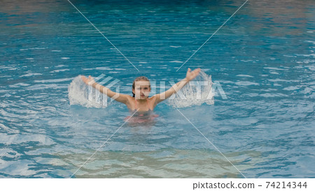 The little cute girl have fun in the pool. The child enjoy summer vacation in a swimming pool jumping, spinning, splash water. Happy childhood. The little cute girl have fun in the pool. The child enjoy summer vacation in a swimming pool jumping, spinning, splash water. Happy childhood. 74214344