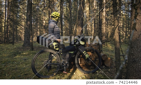 The woman travel on mixed terrain cycle touring with bike bikepacking. The traveler journey with bicycle bags. Magic forest park. The woman travel on mixed terrain cycle touring with bike bikepacking. The traveler journey with bicycle bags. Magic forest park. 74214446