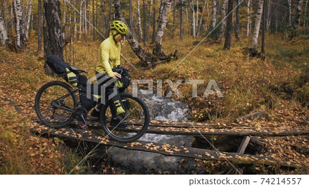 The woman travel on mixed terrain cycle touring with bikepacking. The traveler journey with bicycle bags. Sport tourism bikepacking. The woman travel on mixed terrain cycle touring with bikepacking. The traveler journey with bicycle bags. Sport tourism bikepacking. 74214557