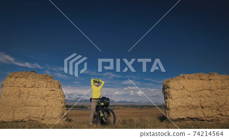 The woman travel on mixed terrain cycle touring with bikepacking. The traveler journey with bicycle bags. Sport tourism bikepacking. The woman travel on mixed terrain cycle touring with bikepacking. The traveler journey with bicycle bags. Sport tourism bikepacking. 74214564
