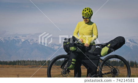 The woman travel on mixed terrain cycle touring with bikepacking. The traveler journey with bicycle bags. Sport tourism bikepacking. 74214581