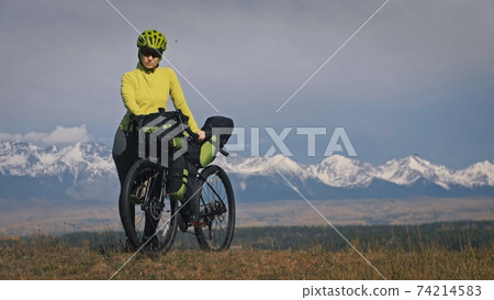 The woman travel on mixed terrain cycle touring with bikepacking. The traveler journey with bicycle bags. Sport tourism bikepacking. The woman travel on mixed terrain cycle touring with bikepacking. The traveler journey with bicycle bags. Sport tourism bikepacking. 74214583