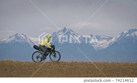 The woman travel on mixed terrain cycle touring with bikepacking. The traveler journey with bicycle bags. Sport tourism bikepacking. 74214612