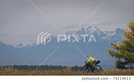 The woman travel on mixed terrain cycle touring with bikepacking. The traveler journey with bicycle bags. Sport tourism bikepacking. The woman travel on mixed terrain cycle touring with bikepacking. The traveler journey with bicycle bags. Sport tourism bikepacking. 74214613