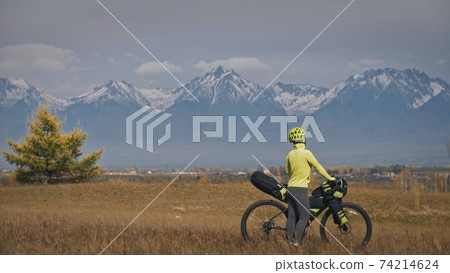 The woman travel on mixed terrain cycle touring with bikepacking. The traveler journey with bicycle bags. Sport tourism bikepacking. The woman travel on mixed terrain cycle touring with bikepacking. The traveler journey with bicycle bags. Sport tourism bikepacking. 74214624