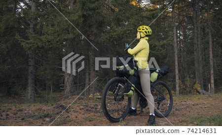 The woman travel on mixed terrain cycle touring with bike bikepacking. The traveler journey with bicycle bags. Magic forest park. The woman travel on mixed terrain cycle touring with bike bikepacking. The traveler journey with bicycle bags. Magic forest park. 74214631