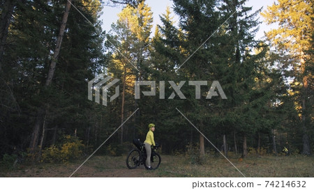 The woman travel on mixed terrain cycle touring with bike bikepacking. The traveler journey with bicycle bags. Magic forest park. The woman travel on mixed terrain cycle touring with bike bikepacking. The traveler journey with bicycle bags. Magic forest park. 74214632