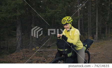 The woman travel on mixed terrain cycle touring with bike bikepacking. The traveler journey with bicycle bags. Magic forest park. The woman travel on mixed terrain cycle touring with bike bikepacking. The traveler journey with bicycle bags. Magic forest park. 74214635
