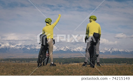 The man and woman travel on mixed terrain cycle touring with bikepacking. The love couple journey with tent in with bicycle bags. Stylish sportswear. The man and woman travel on mixed terrain cycle touring with bikepacking. The love couple journey with tent in with bicycle bags. Stylish sportswear. 74215149