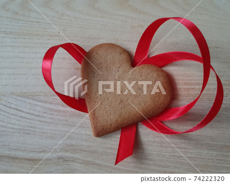 heart-shaped homemade gingerbread decorated with red ribbon on a light wooden background, Valentine's Day, greeting card, pastry, Copy space, top view, love concept, Engagement, love 74222320