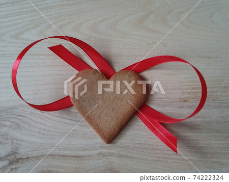 heart-shaped homemade gingerbread decorated with red ribbon on a light wooden background, Valentine's Day, greeting card, pastry, Copy space, top view, love concept, Engagement, love 74222324