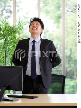 A young man injured his back from using a computer for a long time. 74222504