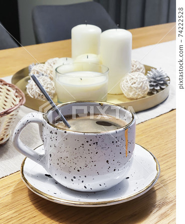 Cup of coffee on the table and a tray with candles 74222528