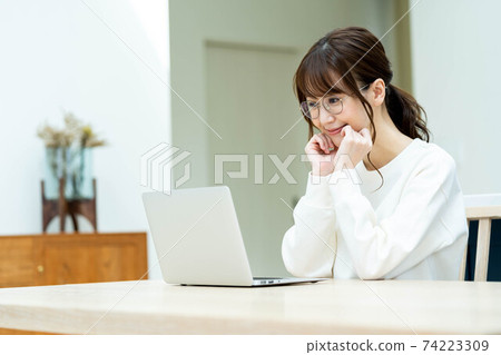 Woman using a laptop at the living room table 74223309