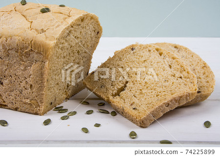 Wheat yeast rustic bread with pumpkin seeds on white wooden board background 74225899