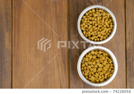 Dry cat food in metal bowl on wooden background. Studio Photo Dry cat food in metal bowl on wooden background. Studio Photo 74226058