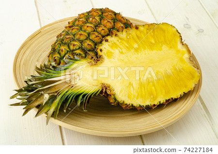 Exotic fruits. Ripe sweet ripe pineapple on wooden background. Studio Photo 74227184