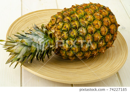 Exotic fruits. Ripe sweet ripe pineapple on wooden background. Studio Photo 74227185