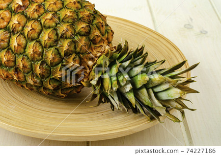 Exotic fruits. Ripe sweet ripe pineapple on wooden background. Studio Photo 74227186