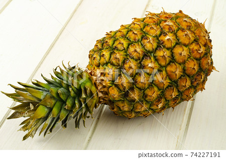Exotic fruits. Ripe sweet ripe pineapple on wooden background. Studio Photo Exotic fruits. Ripe sweet ripe pineapple on wooden background. Studio Photo 74227191