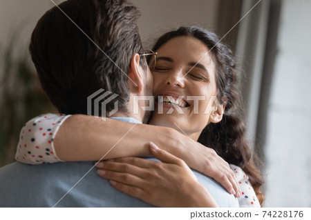 Excited millennial wife embracing beloved husband meeting at home Excited millennial wife embracing beloved husband meeting at home 74228176